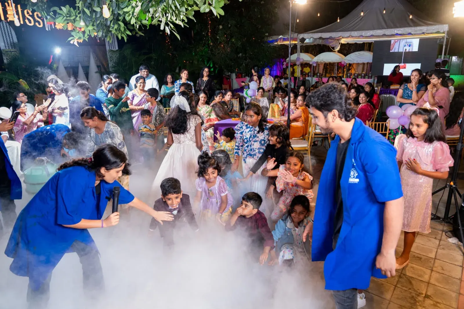 A garden party engulfed in white nitrogen fog, with children and parents watching