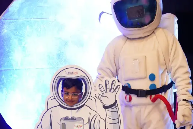 An astronaut mascot standing beside a photo board at a Space Explorers party