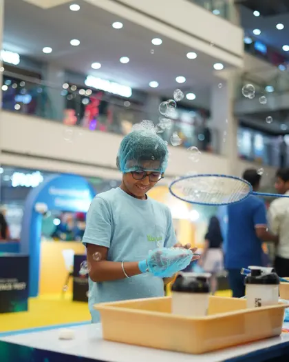 A child drawing a giant bubble ring up out of a tray of solution
