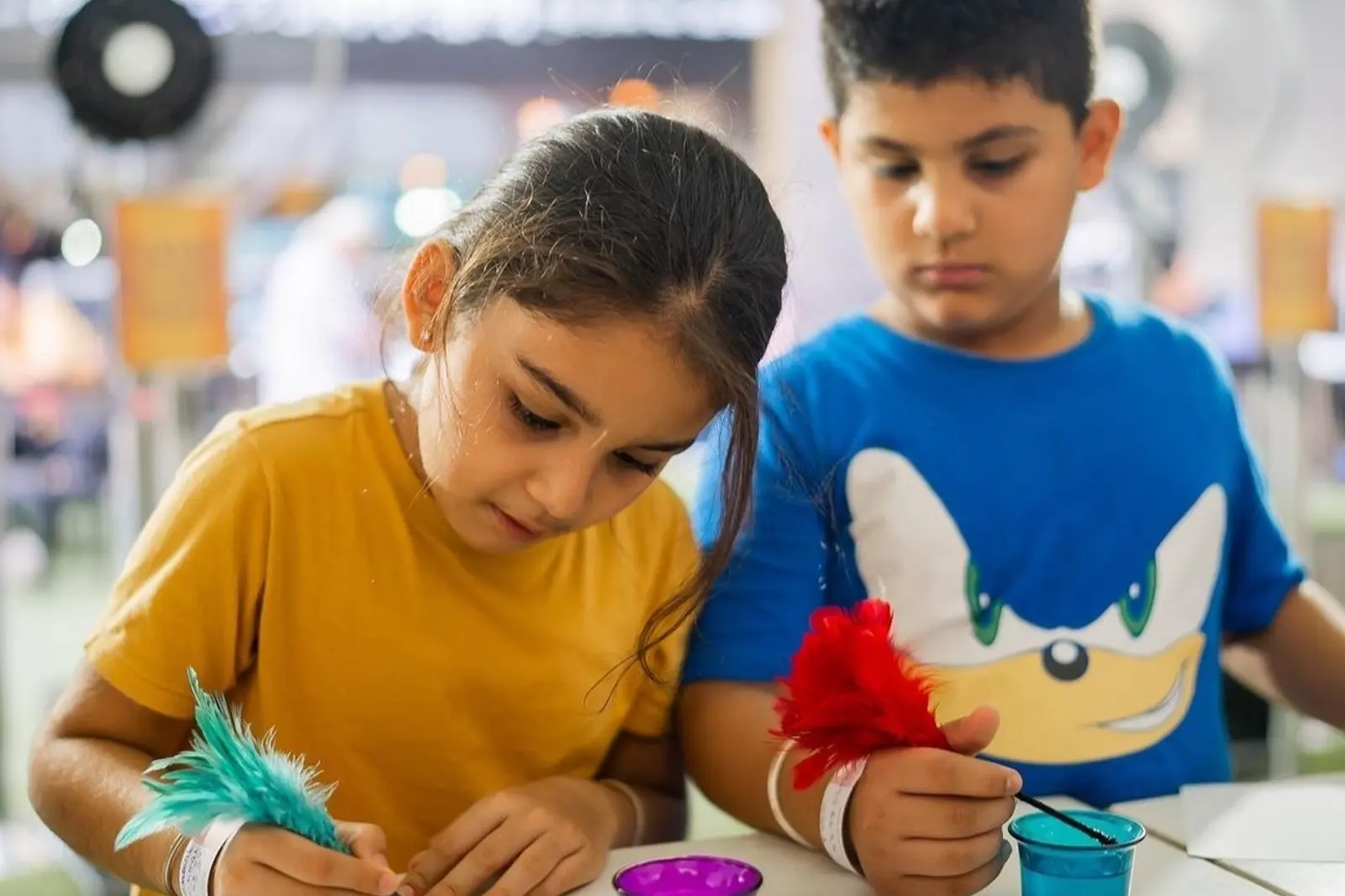 Two children writing with feather quills and coloured ink