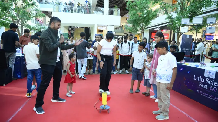 A science-festival concourse, children testing rocket launchers along a red carpet