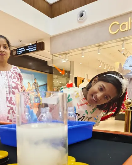 A girl watching foam rise up a measuring cylinder on the activity bench