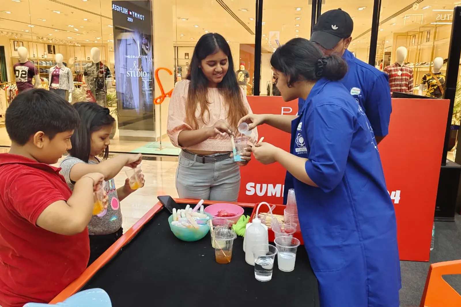 A child pouring a coloured solution into cups at a mall science counter
