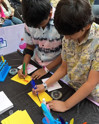 A child painting with a feather quill at a make-and-take craft table