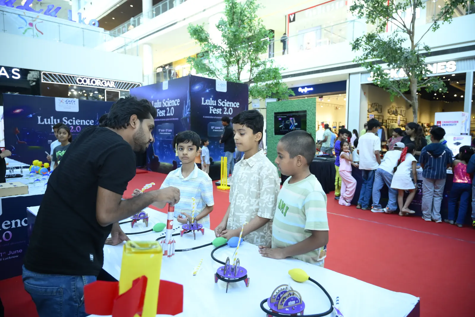 A MakerMasti host setting up rocket launchers with children at a science festival