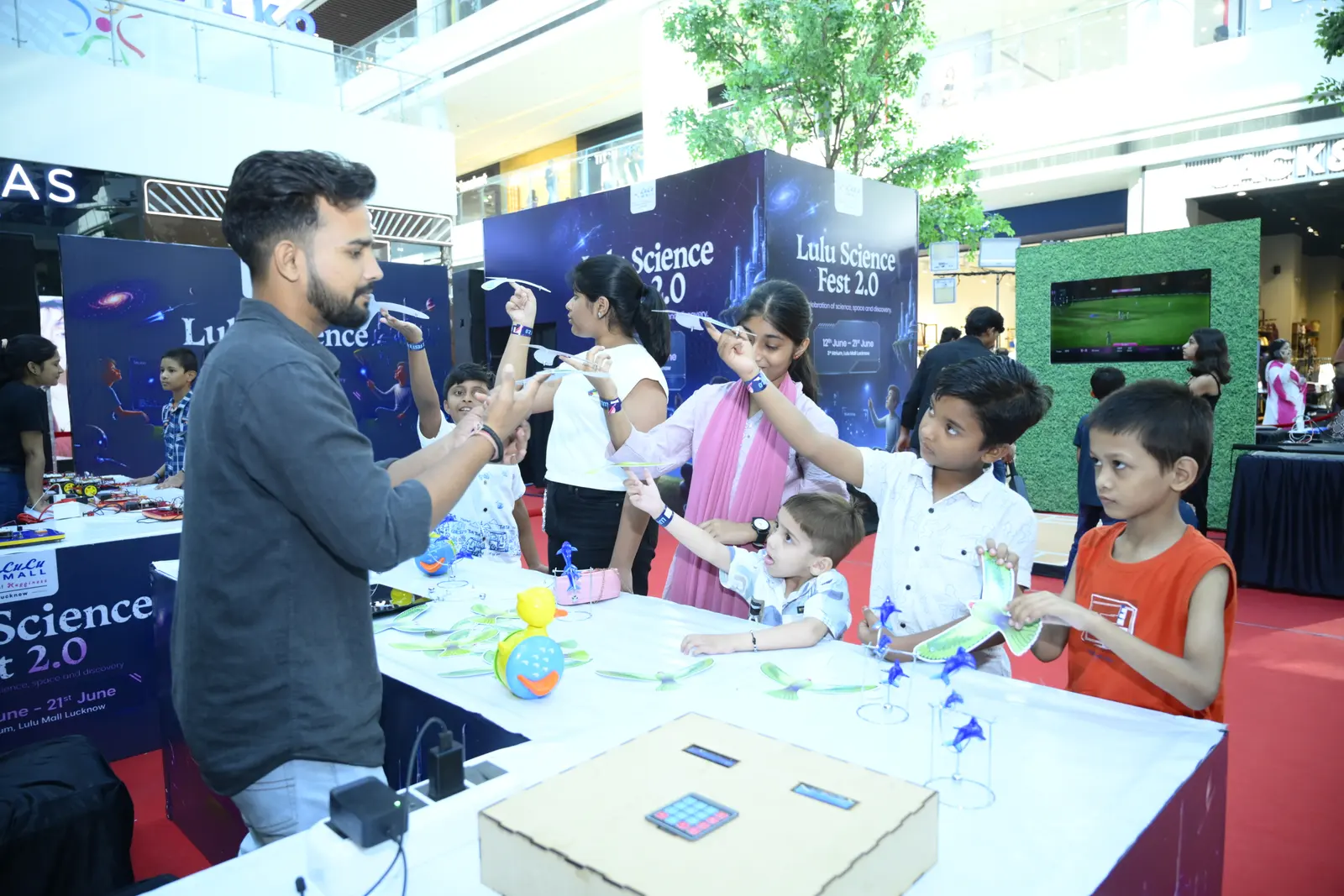 A MakerMasti host running a balancing-bird demonstration at a branded science-fest stand