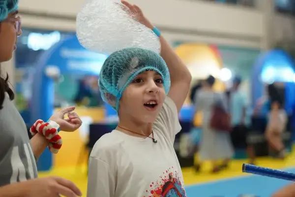 A child producing a long rope of foam bubbles from a bottle