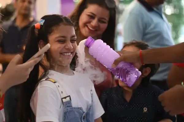 A girl grinning as a MakerMasti host pours foaming potion over her hands
