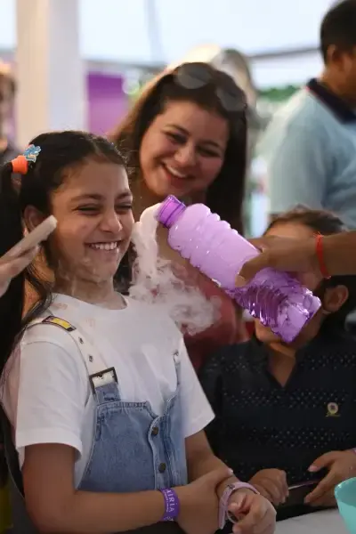 A girl grinning as a MakerMasti host pours foaming potion over her hands