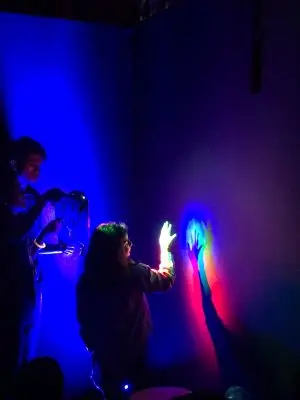 An instructor demonstrating light in a dark room to a child